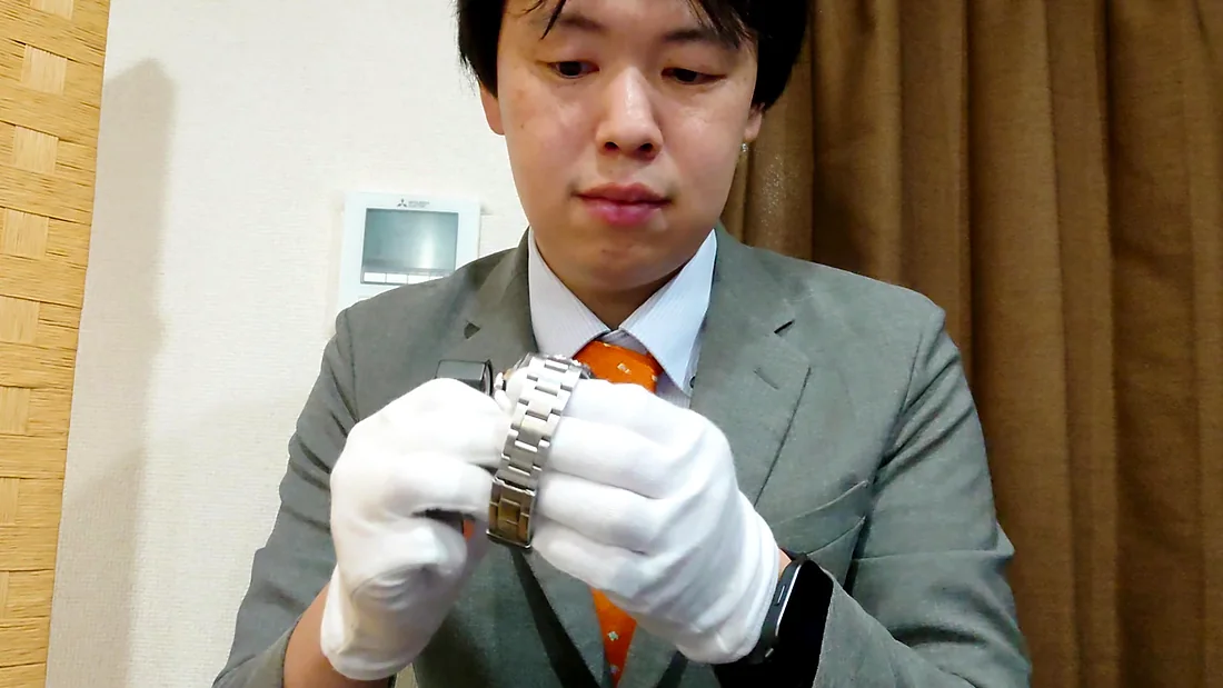 白手袋で腕時計を手に取って確認しているところ