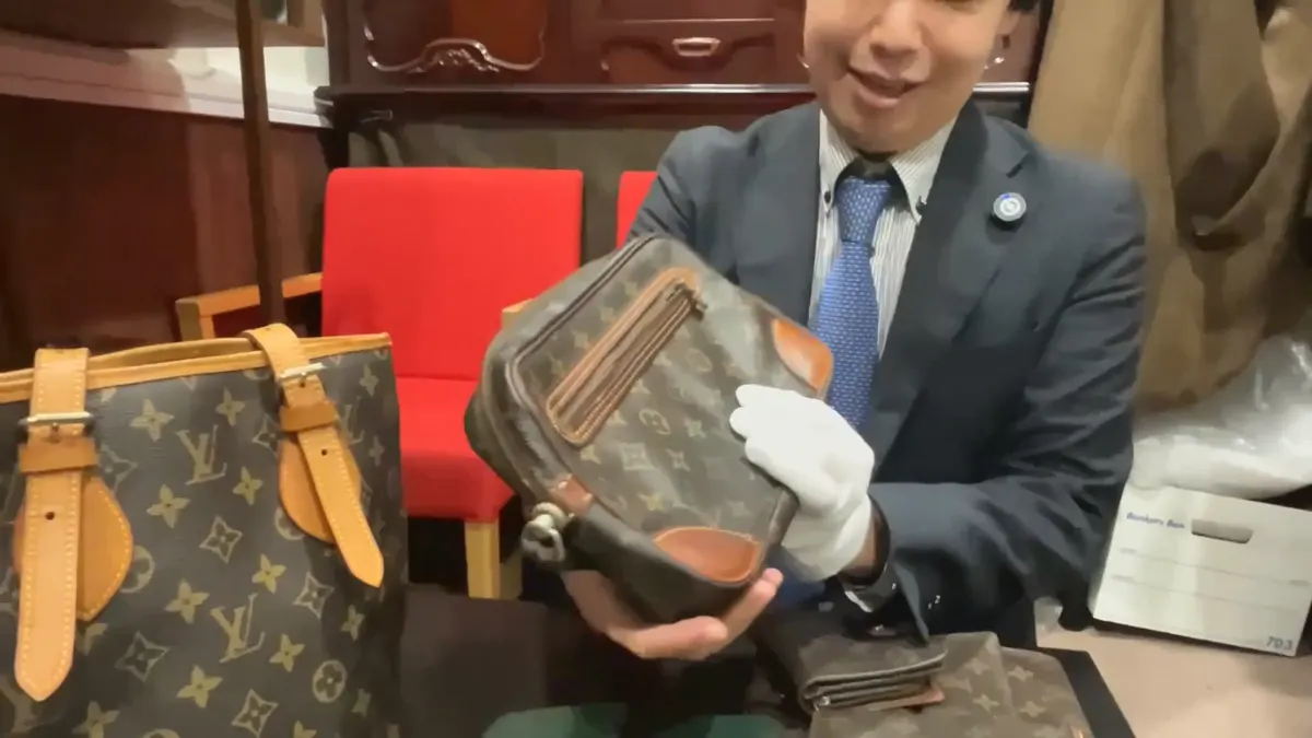 使い込まれたルイ・ヴィトンのモノグラムのセカンドバッグを手に持って見せているところ