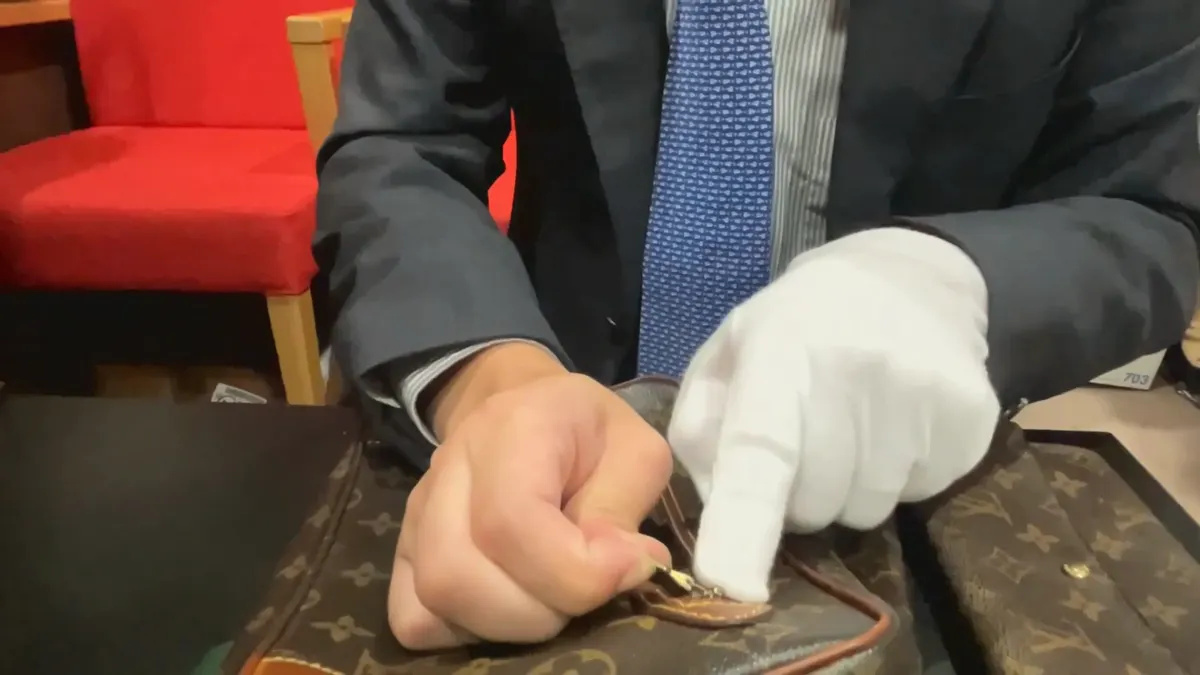 ルイ・ヴィトンのバッグの持ち手の付け根にある金具を指で示しているところ